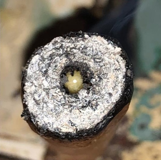 A hash hole is being smoked, the live rosin extract in the middle, and shown from the front.